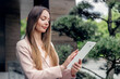 © Evgenia - Attractive smiling caucasian businesswoman standing and looking at tablet screen