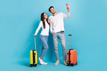 Photo of two positive cheerful glad couple people wear white shirts doing selfie prepared to travel isolated on blue color background