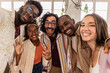group of cheerful mutliracial coworkers taking selfie using smartphone in backlit loft office