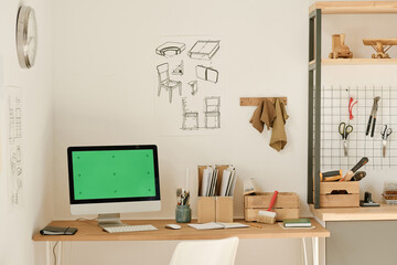 Horizontal image of workplace with computer on table and blueprints on the wall in workshop