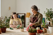 © AnnaStills - Woman and girl with down syndrome wearing rubber gloves to plant plants at table