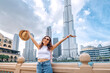 © EdNurg - happy traveler girl with outstretched arms, embracing the incredible view of majestic tower in Dubai, UAE