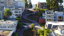 Aerial Shot Of Vehicles On Lombard Street Amidst Houses, Drone Flying Backward Over City Against Sky - San Francisco, California