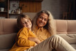 © nenetus - smiling and relaxed confident grandma resting on the sofa with his grandson in her comfortable white home.Generative AI
