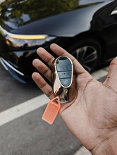 a modern electronic wireless car key with futuristic design in palm of hand used for keyless entry and to lock or unlock the vehicle