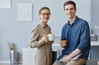 © Seventyfour - Portrait of two young business people man and woman looking at camera in office holding coffee cups during break, copy space