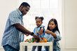 © Art_Photo - Portrait of happy love black family african american father and mother with little girl smiling activity learn and skill brain training play with toy build wooden blocks board education game at home