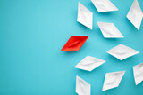 Fototapeta Do przedpokoju - Leadership concept. Red leader paper ship leading among white on blue background.