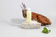 cosmetics container on the podium made of stone, tree bark, lavender twigs and mint leaves on a gray background