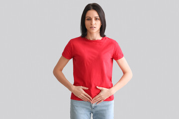 Wall Mural - Young woman with menstrual cramps on grey background