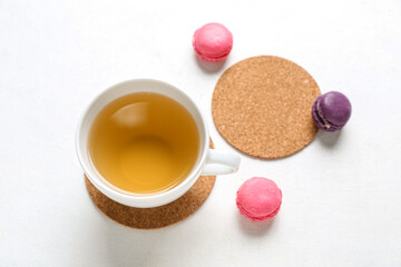 Wall Mural - Drink coasters with cup of tea and macaroons on white table