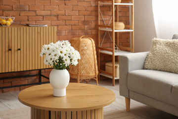 Interior of living room with grey sofa and chrysanthemum flowers on wooden coffee table