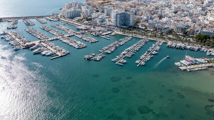 Wall Mural - Aerial drone photo of the town of Sant Antoni on the island of Ibiza in the Balearic Islands Spain showing the boating harbour with parked up boats by costal front with hotels and apartments.