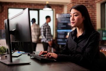 asian software developer working with html script on terminal window, sitting at desk analyzing java
