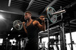 © Богдан Маліцький - african american man lifts barbell in dark gym, sports guy trains in fitness room and goes in for sports