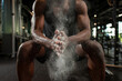 © Богдан Маліцький - sporty african american man trains in dark gym and rubs his hands with magnesia, young guy makes clap