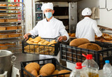 Fototapeta Do przedpokoju - Portrait of baker in protective mask with fresh bread at the bakery
