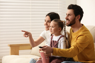 Canvas Print - Happy family watching TV with popcorn on sofa indoors, space for text