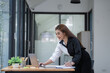 © Songsak C - Happy young Asian businesswoman standing using laptop computer at office.