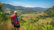© wetzkaz - young adult woman with backpack hiking in summer nature in rural area with flat mountains and hills, meadow on dirt trail, trekking and camping in nature