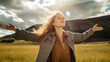 © wetzkaz - young adult woman with outstretched arms and open hands, mountains, fictional place