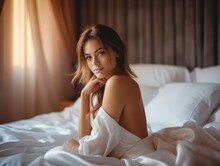 Beautiful Woman Is Waking Up In The Morning, Lying In Bed, Sun Shines On Her From The Big Window. Happy Young Girl Greets New Day With Warm Sunlight Flare.