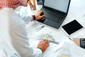 Poster - Young muslim businessman in traditional outfit working at the table in office