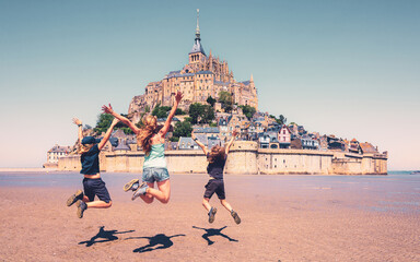 happy family jumping in front of mont saint michel- vacation, travel destination, tour tourism conce