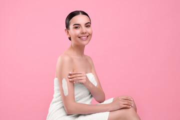 Poster - Beautiful woman with smear of body cream on her arm against pink background