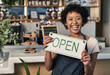 © Allistair/peopleimages.com - Happy woman, open sign and portrait of waitress at cafe in small business, morning or ready to serve. Female person, restaurant owner or server holding board for coffee shop or cafeteria opening