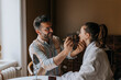 © Maskot - Smiling boyfriend applying make-up to non-binary person at home