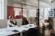 © Maskot - Business colleagues conducting meeting in board room at office seen through glass