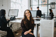 © Maskot - Portrait of smiling businesswoman sitting at corporate office