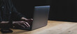 © Rokas - Man hands and Laptop on wooden table. Copy space on black background.