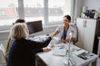 © Maskot - Senior woman doing handshake with female doctor at desk in clinic