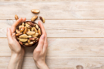 Wall Mural - Woman hands holding a wooden bowl with brazil or bertholletia nuts. Healthy food and snack. Vegetarian snacks of different nuts