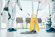 © Felix/peopleimages.com - Covid disinfection, cleaning hospital floor with mop and healthcare compliance for safety and hygiene. Disinfecting liquid, cleaner people in PPE for protection from corona virus with medical policy