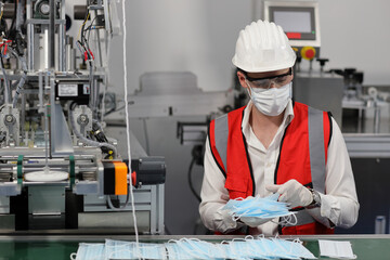 Wall Mural - Caucasian mechanic technician maintenance or PPE inspecting quality of mask and medical face mask production line in factory, manufacturing industry and factory concept.