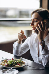 Canvas Print - Portrait of business woman drinking coffee and eating salad in a cafe