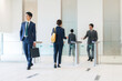 © metamorworks - Group of business people walking in office building lobby.