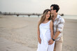 © Bojan - Portrait of young couple lovers, standing together on beach and sharing romantic emotions to each other, relaxed on walkway path outdoors at sunset.