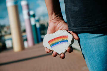 Poster - man has a rock with a rainbow flag in his hand