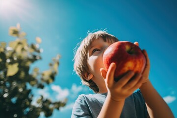 Wall Mural - A young boy holding an apple up to his face. Generative AI image.