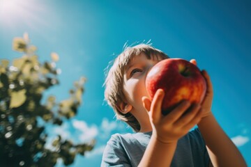 Sticker - A young boy holding an apple up to his face. Generative AI image.