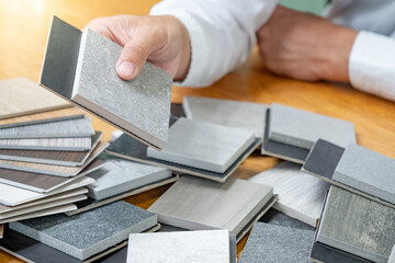 Wall Mural - architect hand choosing sample of stone and wood material or tile texture collection on the table in