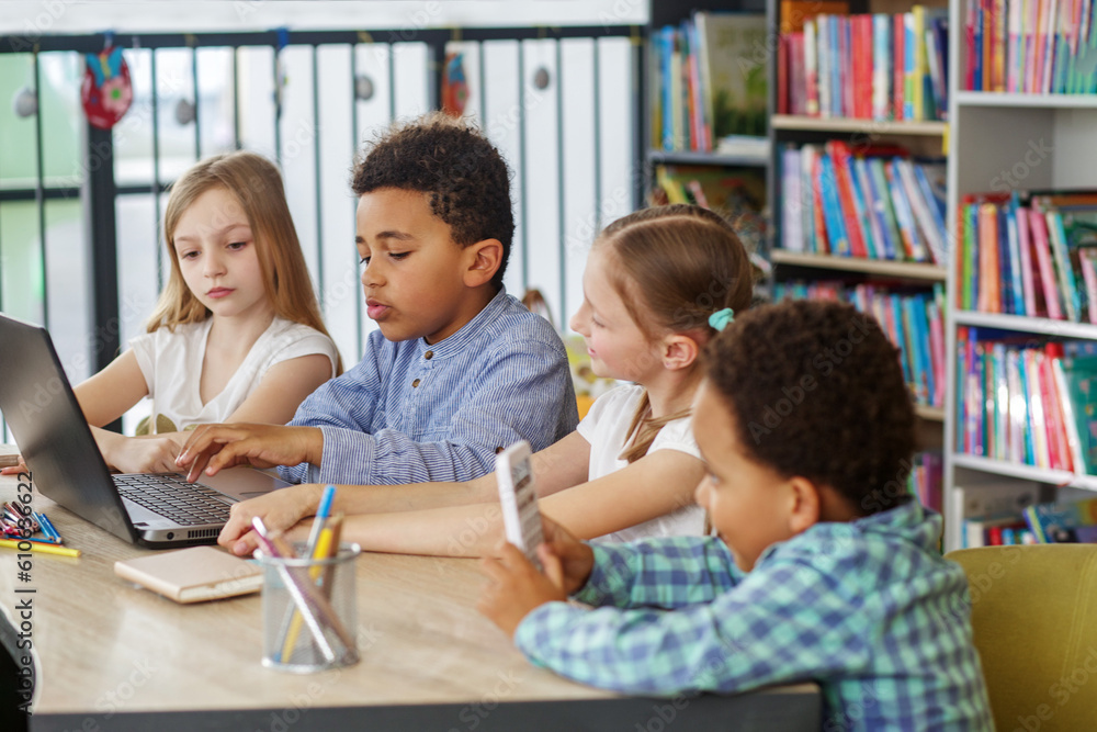 Side view at multiracial group of children sitting in row at school ...