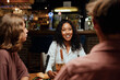 © StratfordProductions - Happy young multiracial group of friends in casual clothing talking during dinner at restaurant