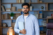 © Ivan - Smiling IT worker in blue shirt look at camera holding laptop at office. concept of remote and freelance work. millennial successful man in glasses