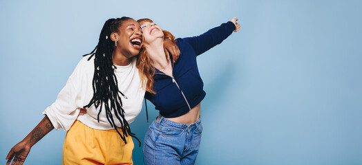 Two happy best friends laughing and having a good time while embracing each other