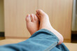 Close-up of man's feet crossed over relaxing in jeans on leather bed in room